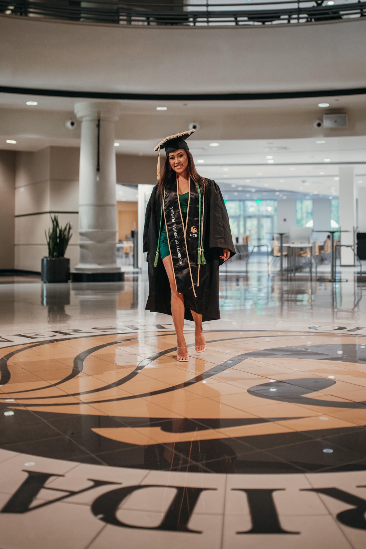 Graduate walking across the Pegasus seal in the Student Union